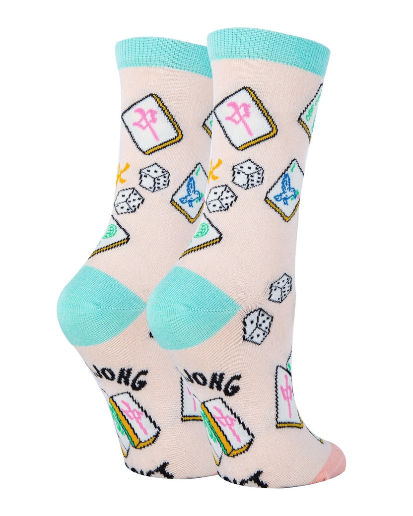 Back view of a pair of pale pink Mahjong-themed socks with aqua heels, colorful tile illustrations, and black printed lettering near the ankles.