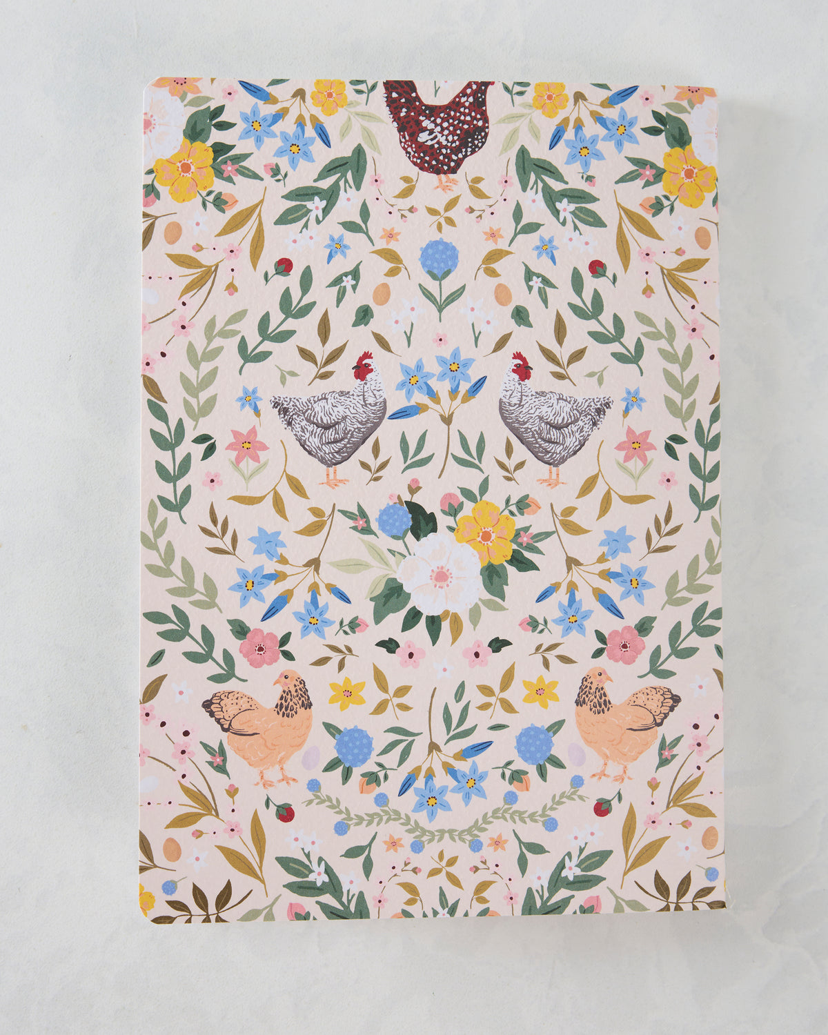 Notebook cover with mirrored chickens, flowers, leaves, and botanical motifs on a light background.