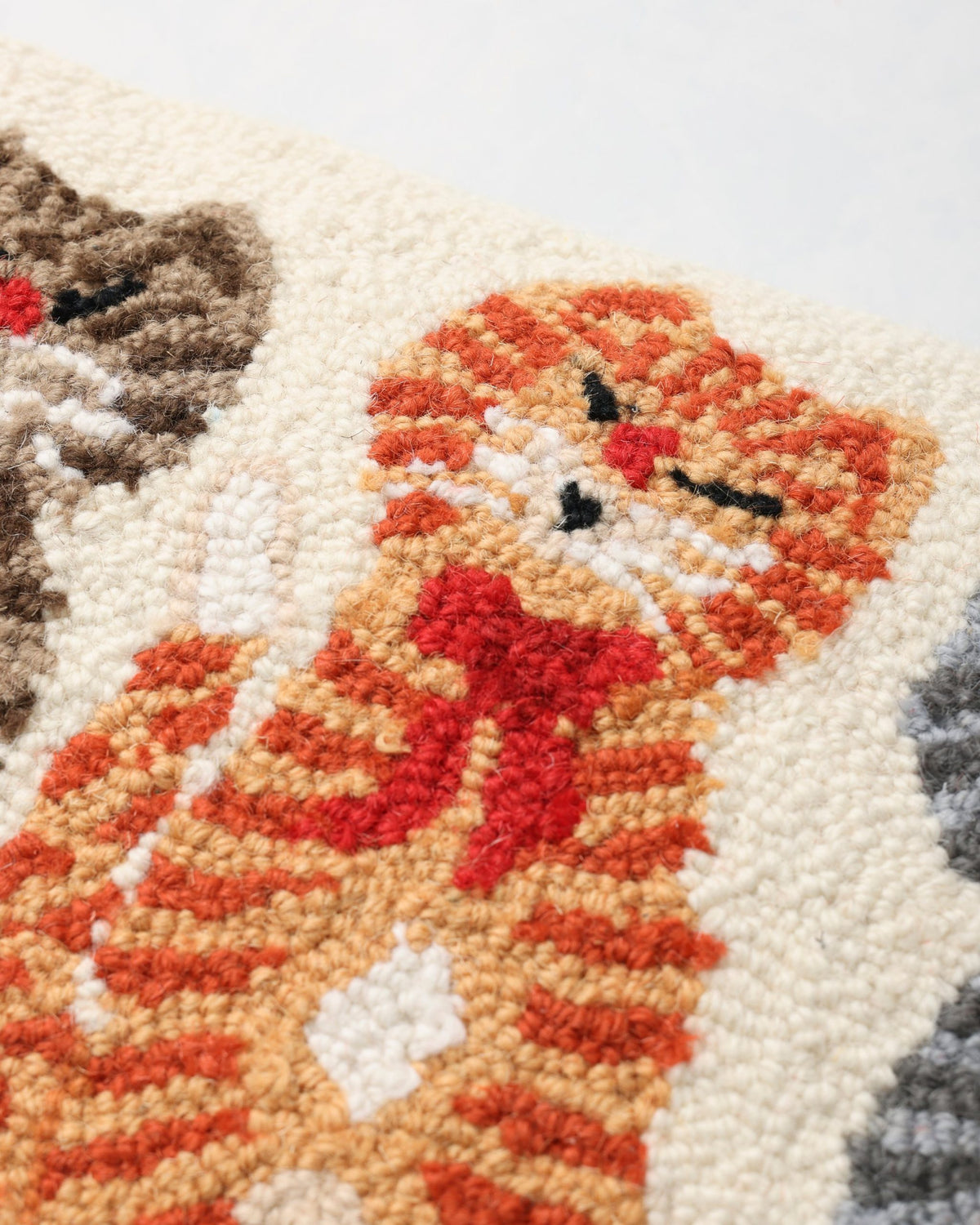 Close-up of the orange cat and red bow on the hooked pillow.