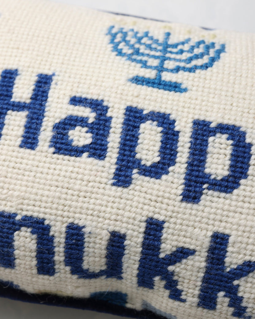 Close-up of the blue needlepoint lettering and menorah motif on the Hanukkah pillow.