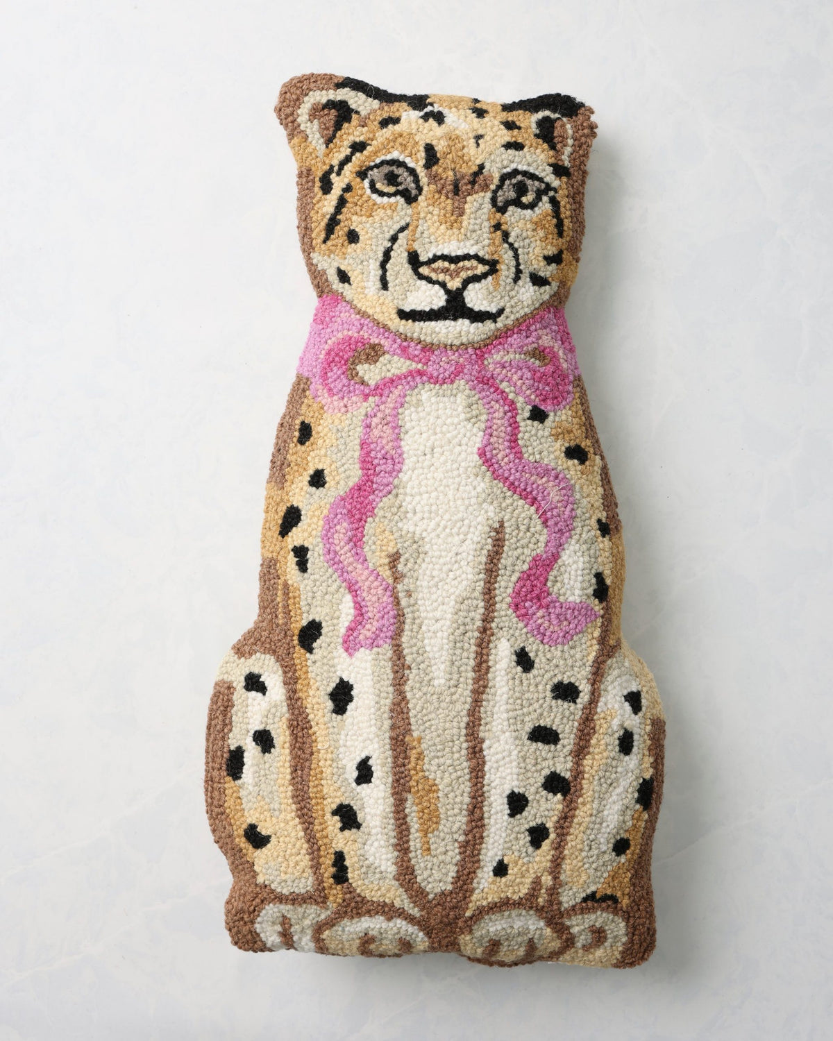 Front of a hooked leopard pillow with a pink bow.