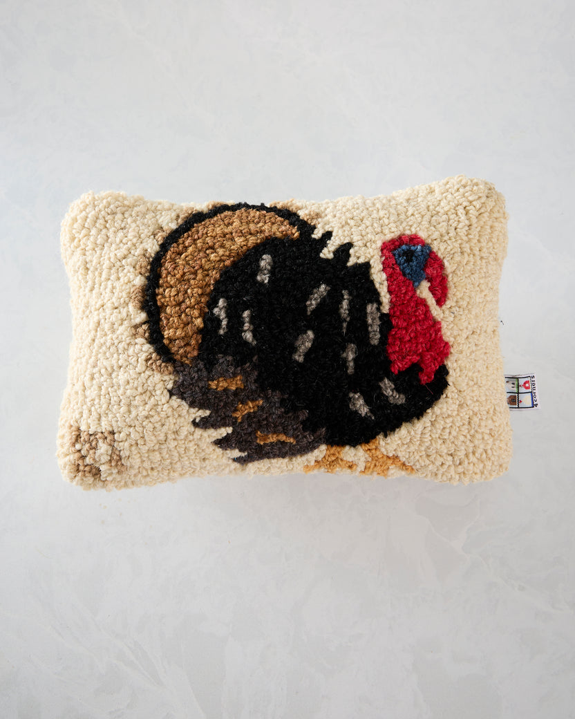 Front view of an ivory Perky Turkey pillow with a large black turkey illustration, brown hat, and red accent.