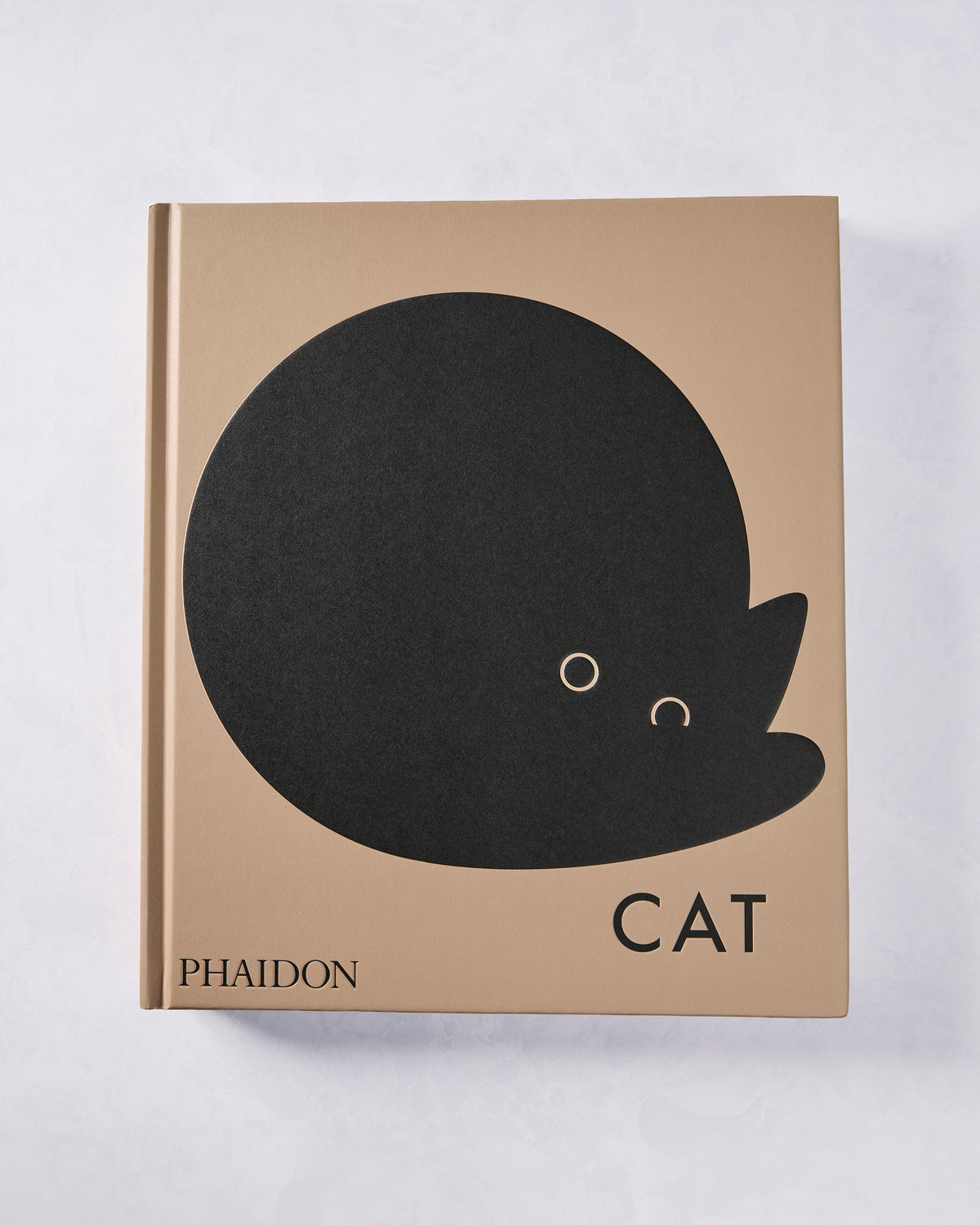 Front cover of the tan Phaidon book “CAT,” featuring a large black cat silhouette.