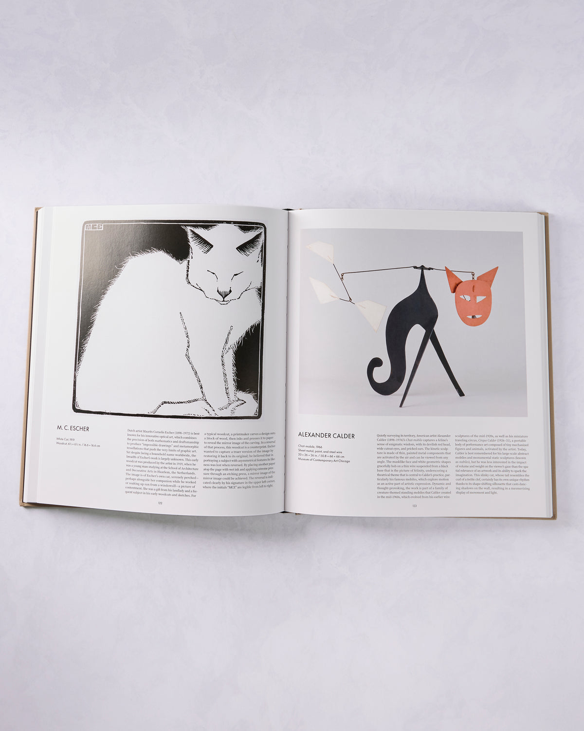 Open book spread featuring a black-and-white cat artwork by M. C. Escher and a Calder cat sculpture with a red mask.