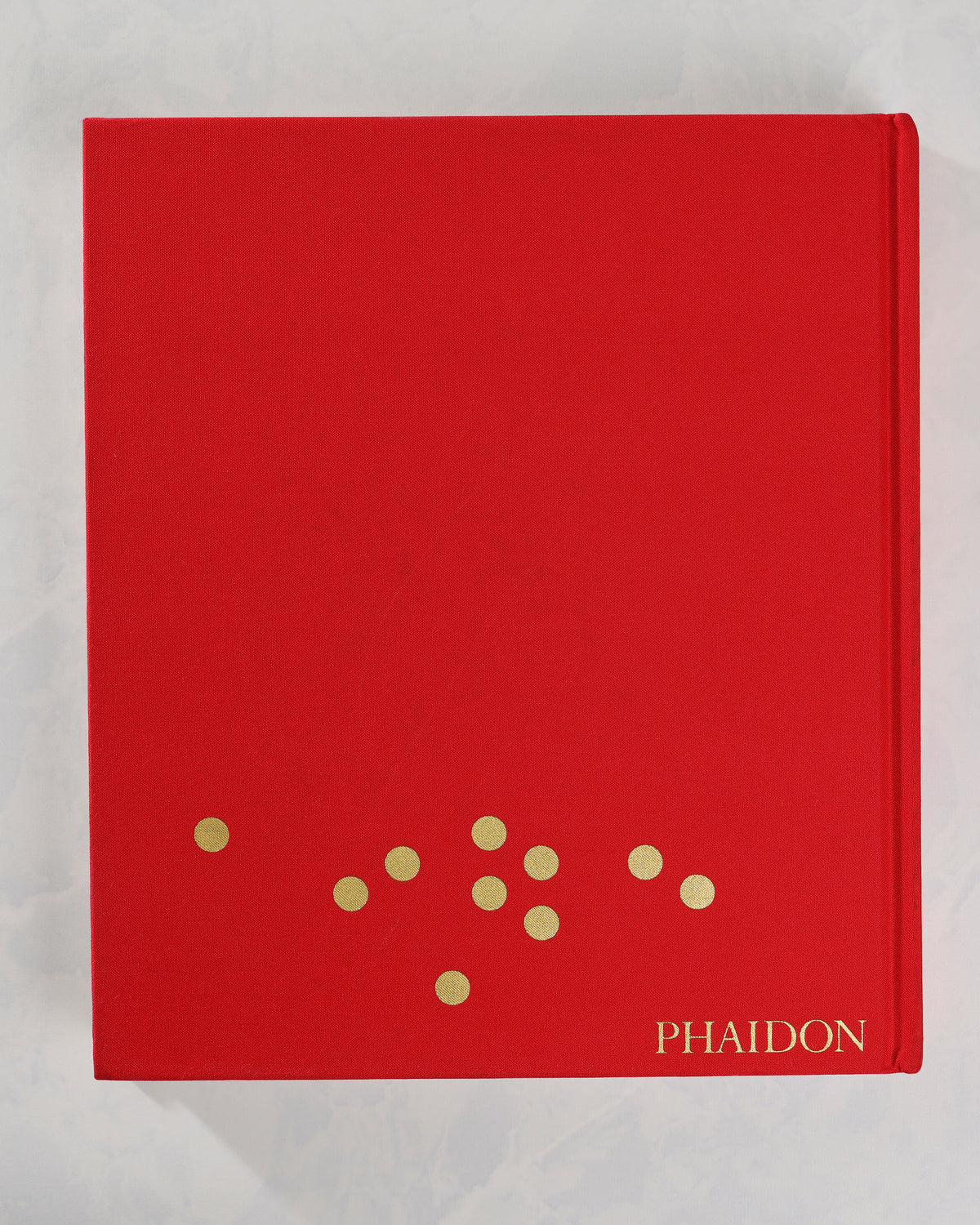 Back cover of the red Christmas Book by Phaidon, with a small arrangement of gold dots near the bottom.