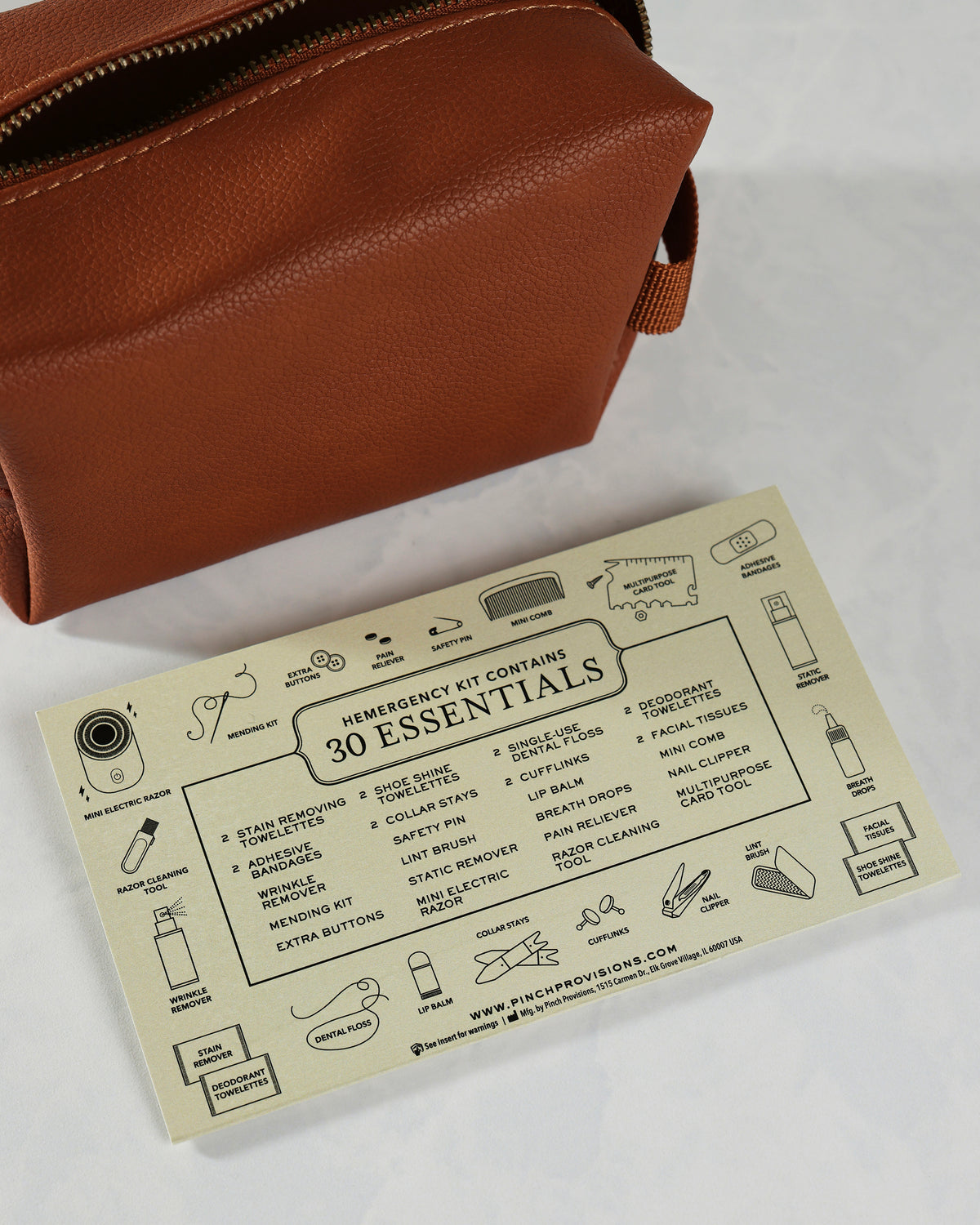 Open cognac-colored Hemergency Kit pouch beside an illustrated card listing its 30 included essentials.
