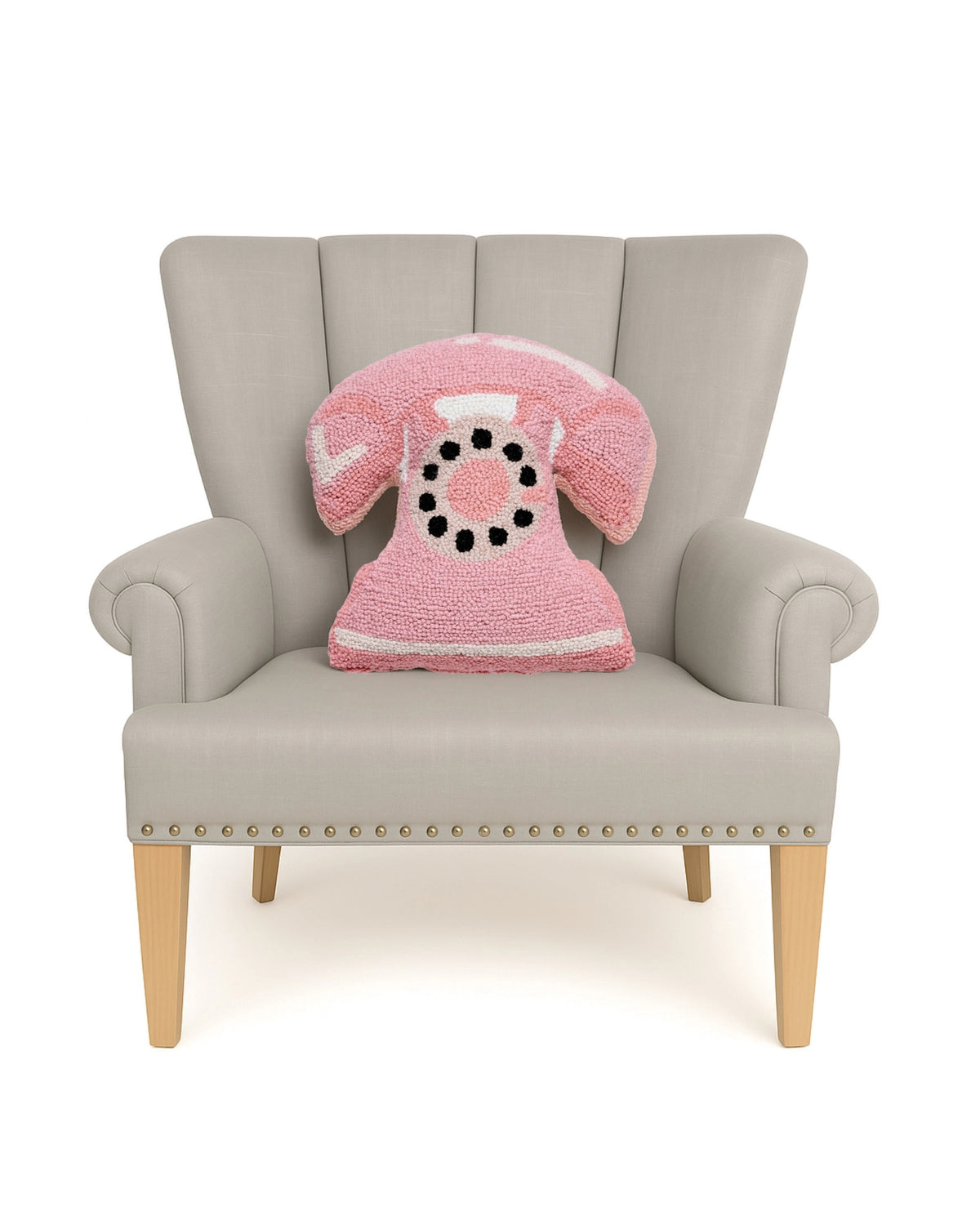 Pink telephone-shaped hook pillow displayed on a light upholstered armchair