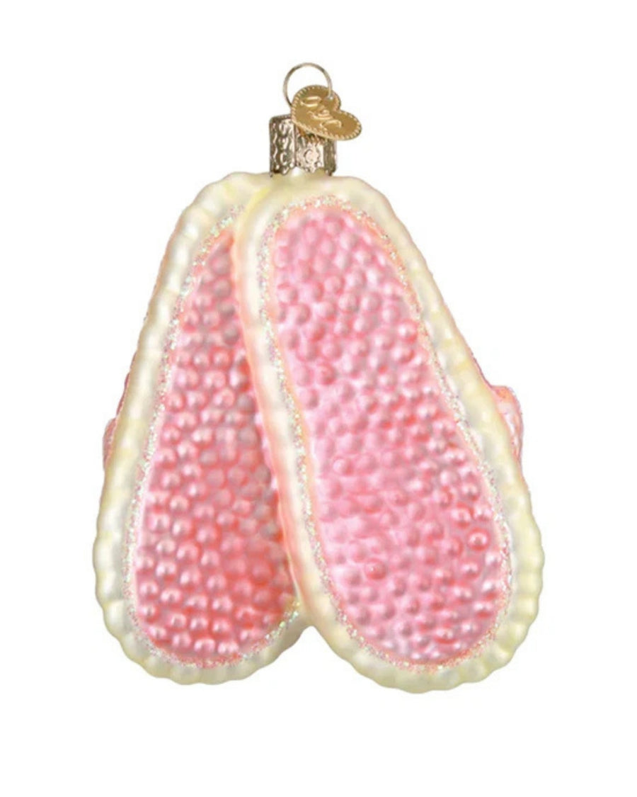 Back view of a pink glitter slipper ornament showing textured pink insoles, cream-colored edging, and a hanging loop.