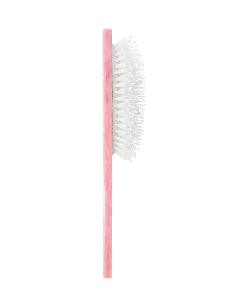 Side view of the pink brush showing the thickness of the handle and white bristles.