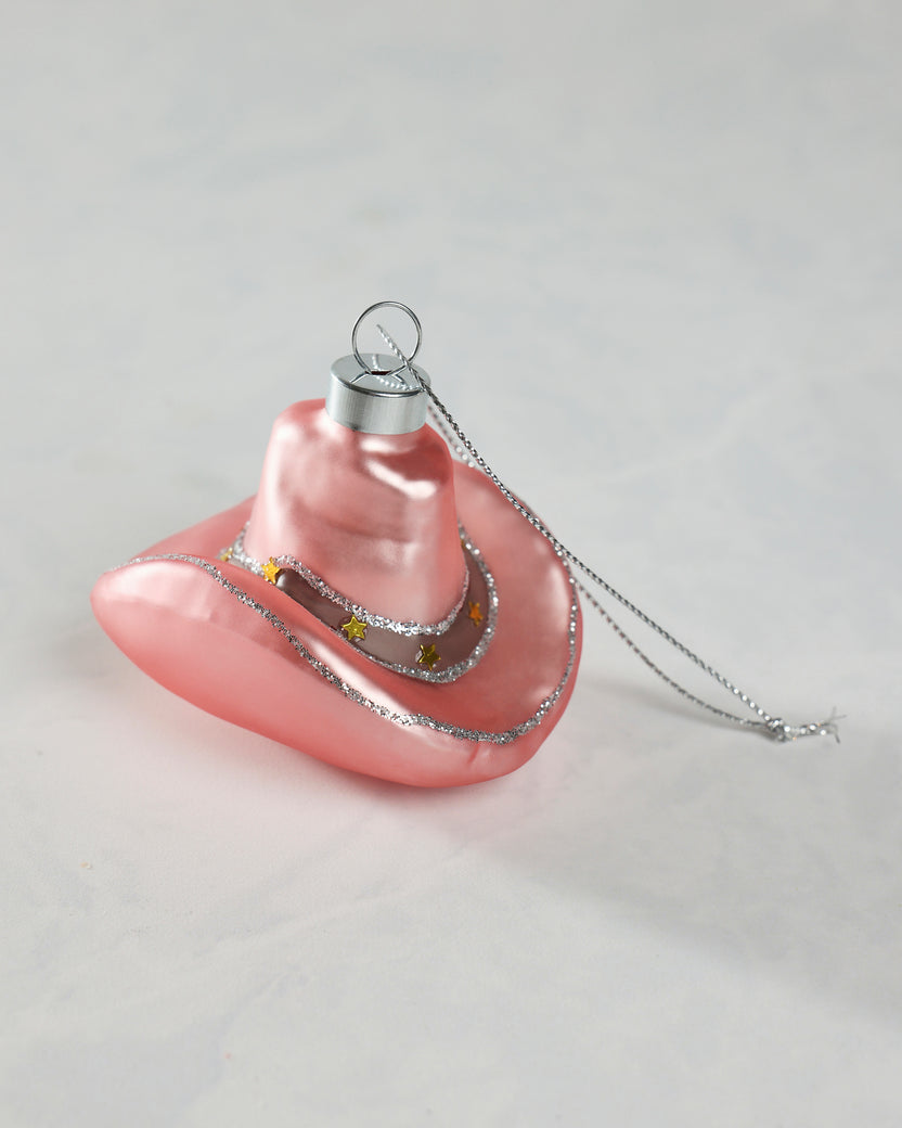 Pink cowgirl hat glass ornament shown from the front, with silver glitter trim, gold star accents, and a hanging loop.