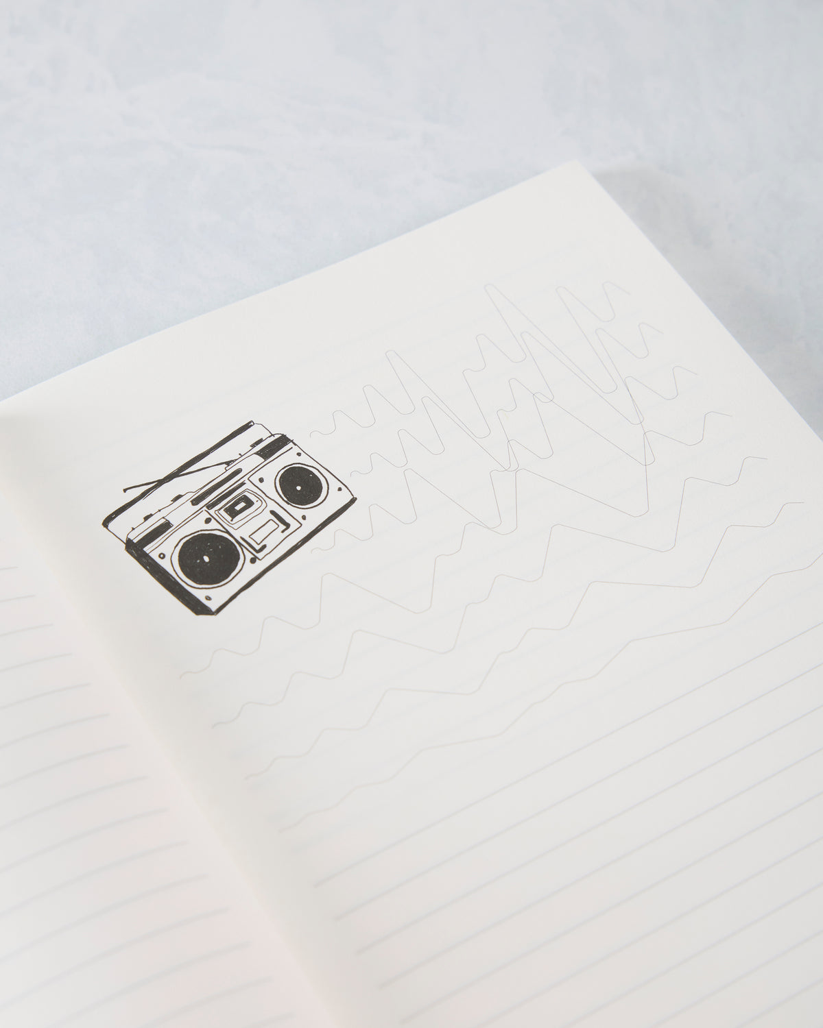 Open sunflower journal showing a lined page with a boombox illustration and faint abstract line drawings.