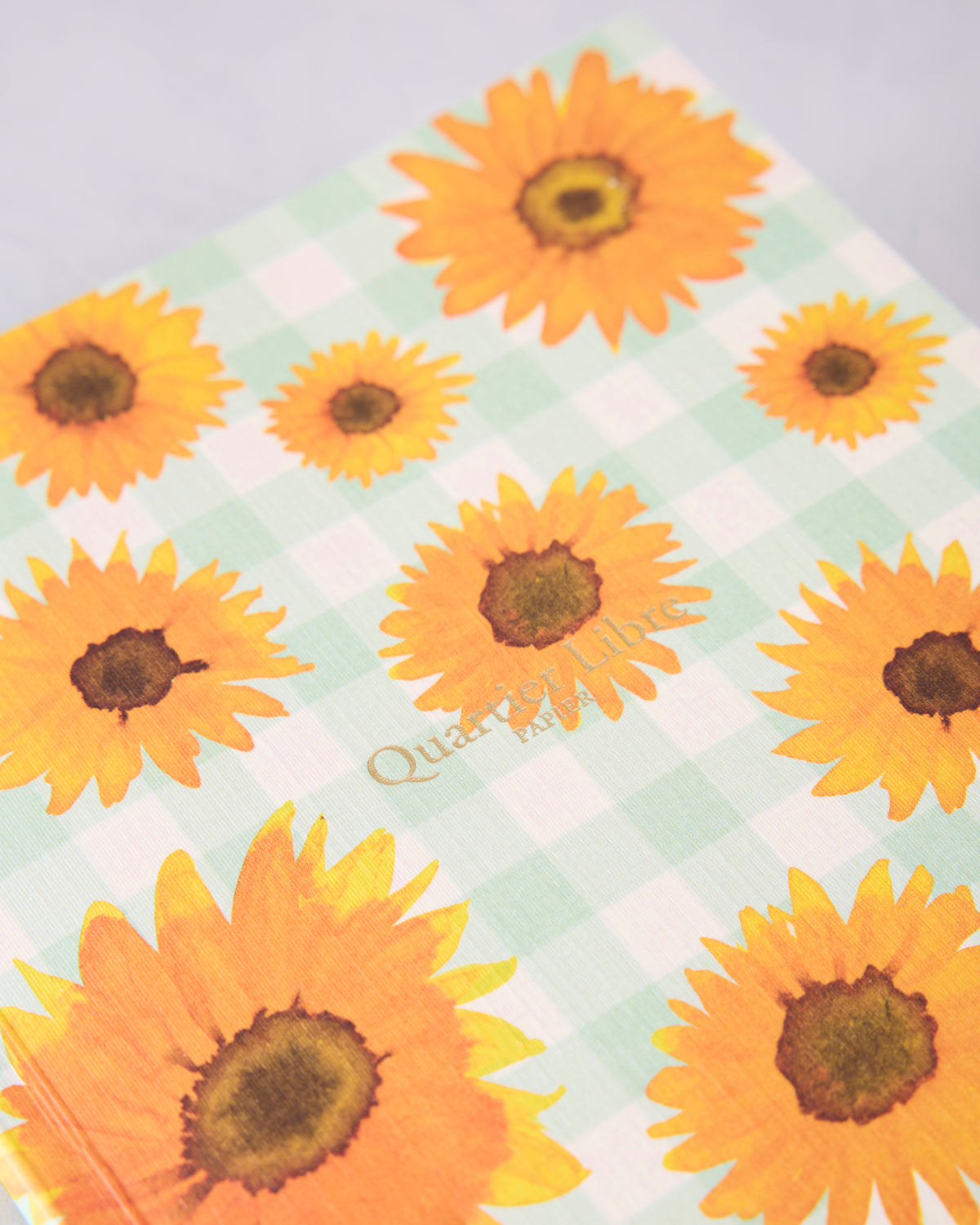 Close-up of the sunflower journal cover showing orange sunflowers on a pale green-and-white checkered background.