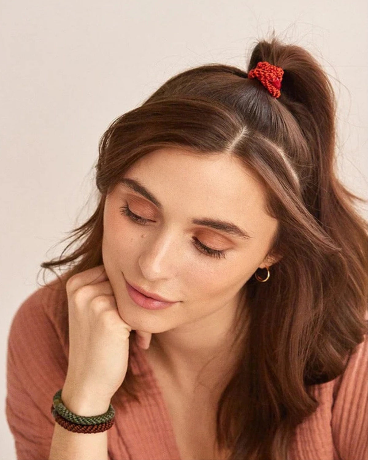 Person wearing a red hair tie in a ponytail and three matching hair ties on the wrist.
