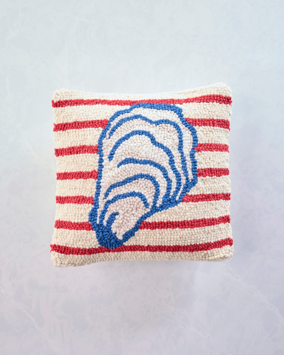 Square cream pillow with horizontal red stripes and a large blue-outlined oyster shell on the front.