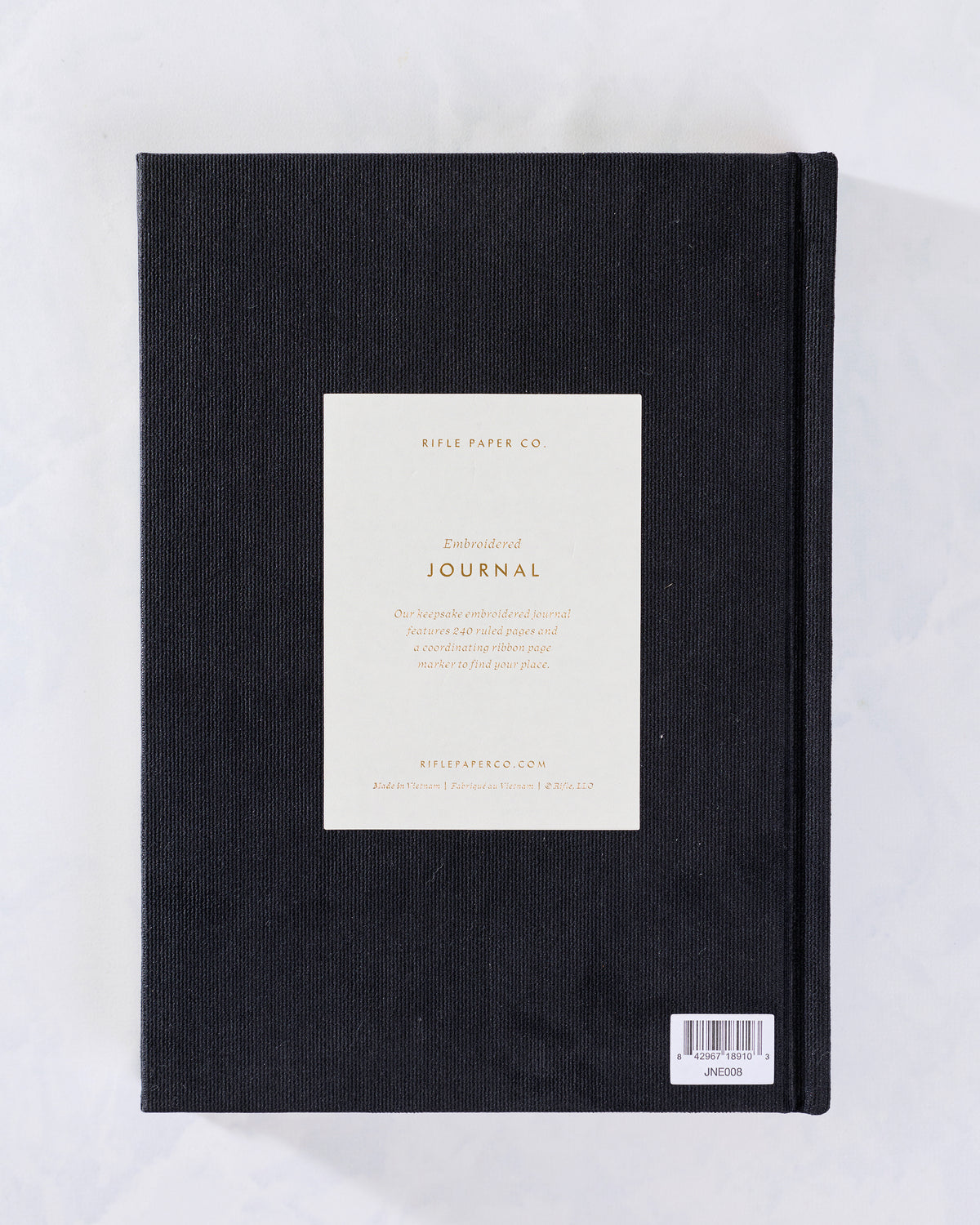 Back cover of the black embroidered journal with a centered product information card and barcode label.