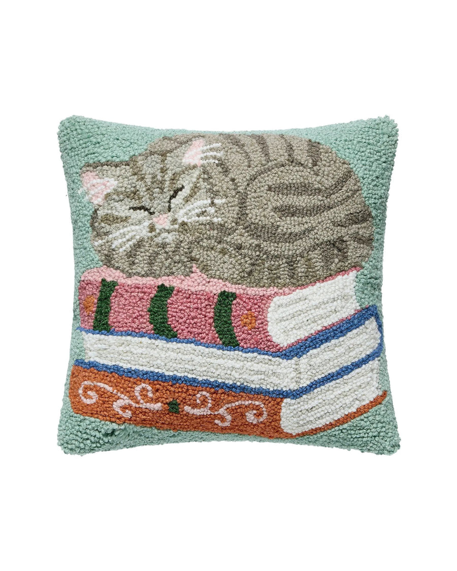Square pillow depicting a sleeping cat curled on top of a stack of books.