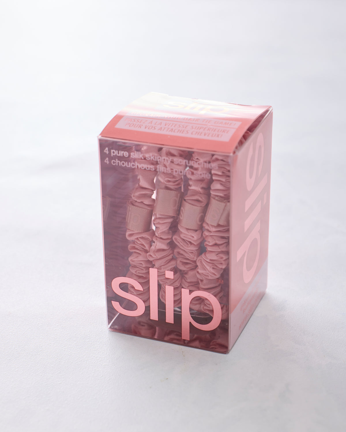 Box of four rose skinny scrunchies by Slip in a clear pink package.