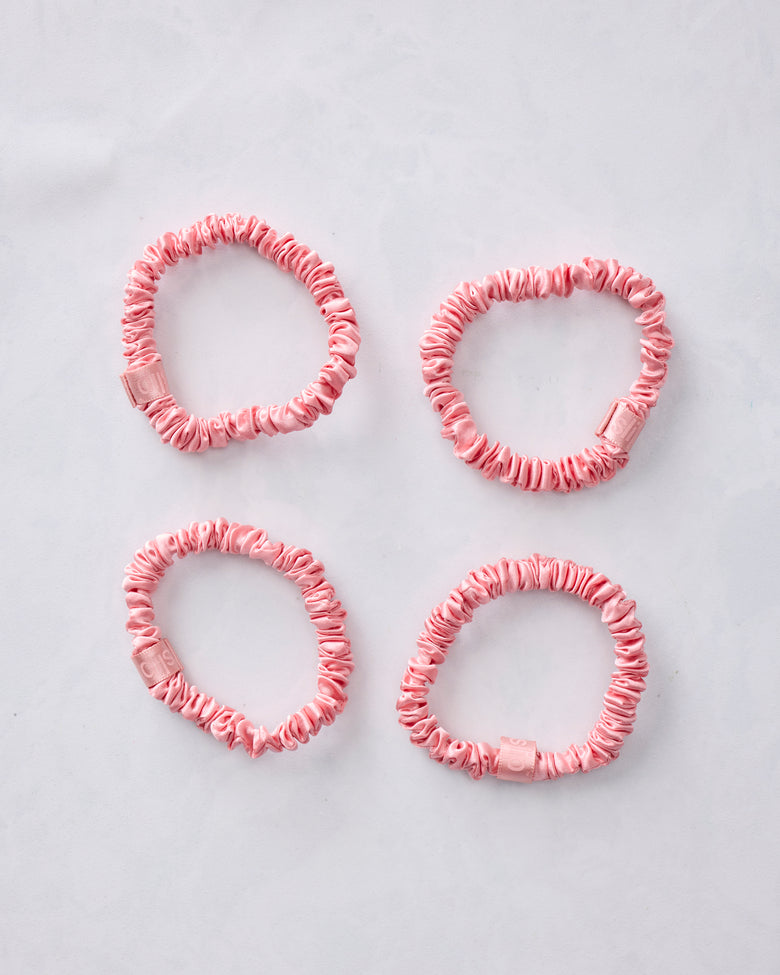Set of four pink skinny scrunchies arranged separately on a light background.