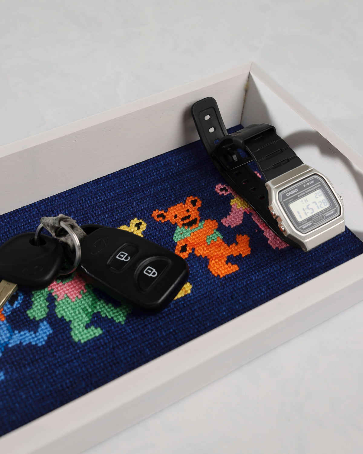 Dark navy dancing bears valet tray shown holding car keys and a digital wristwatch.
