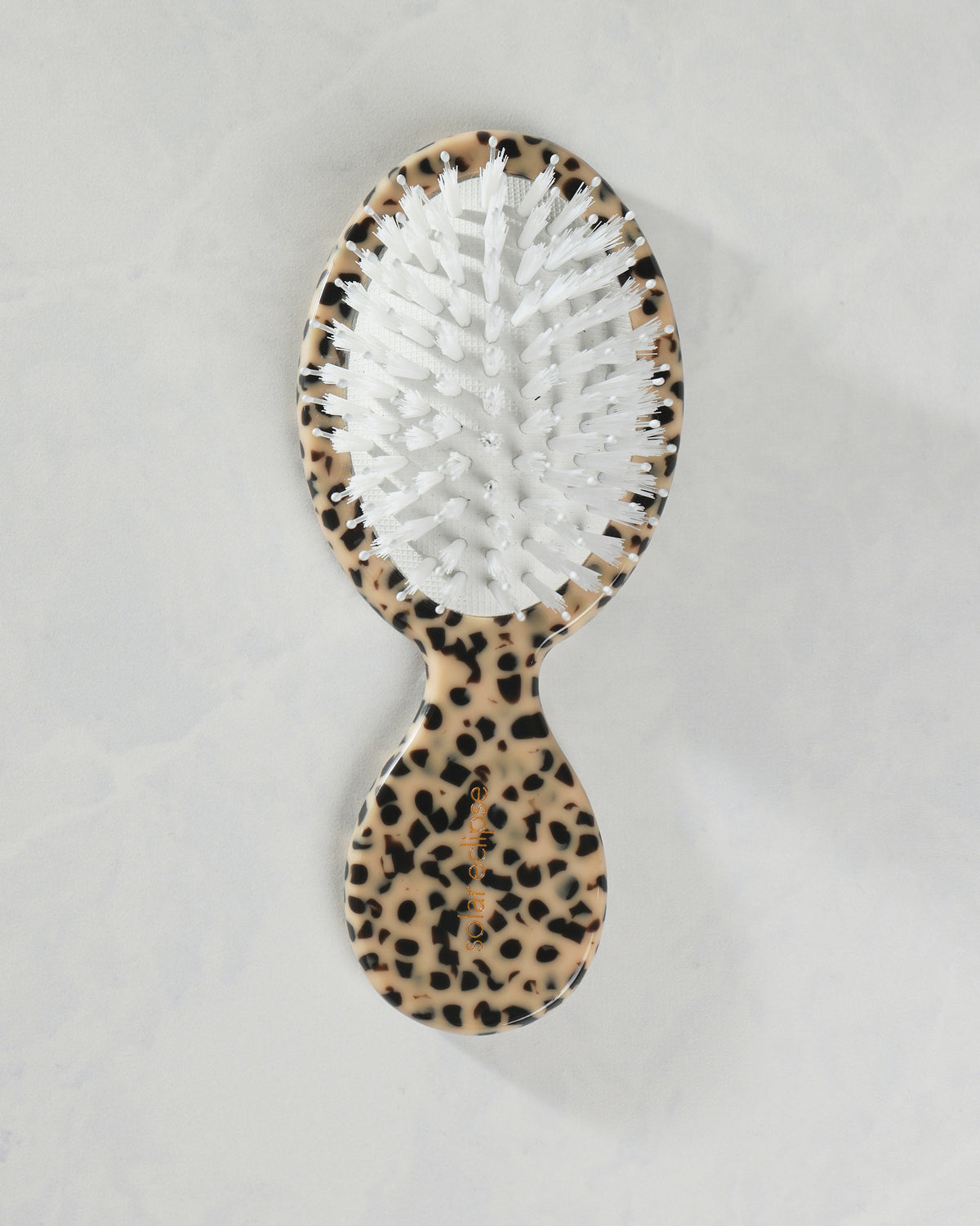 Front view of a leopard-pattern handbag hairbrush with white dual bristles and a compact rounded handle.