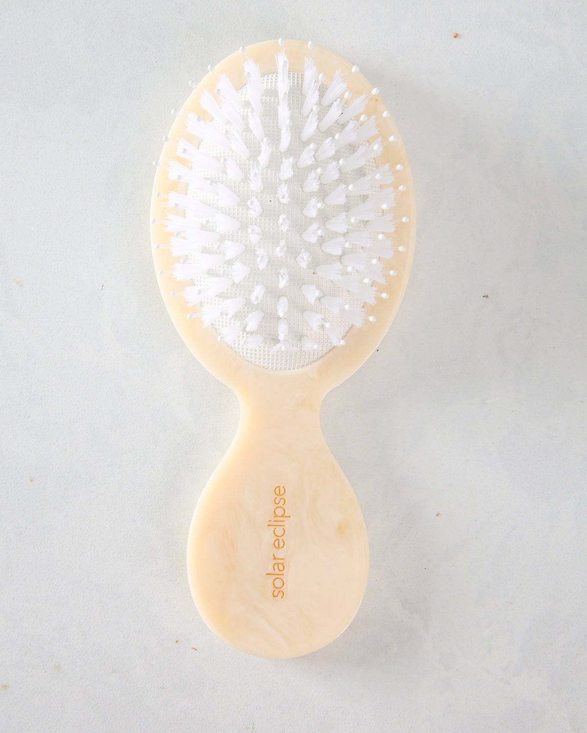 Back of the cream hairbrush showing white bristles and the handle marked “solar eclipse.”