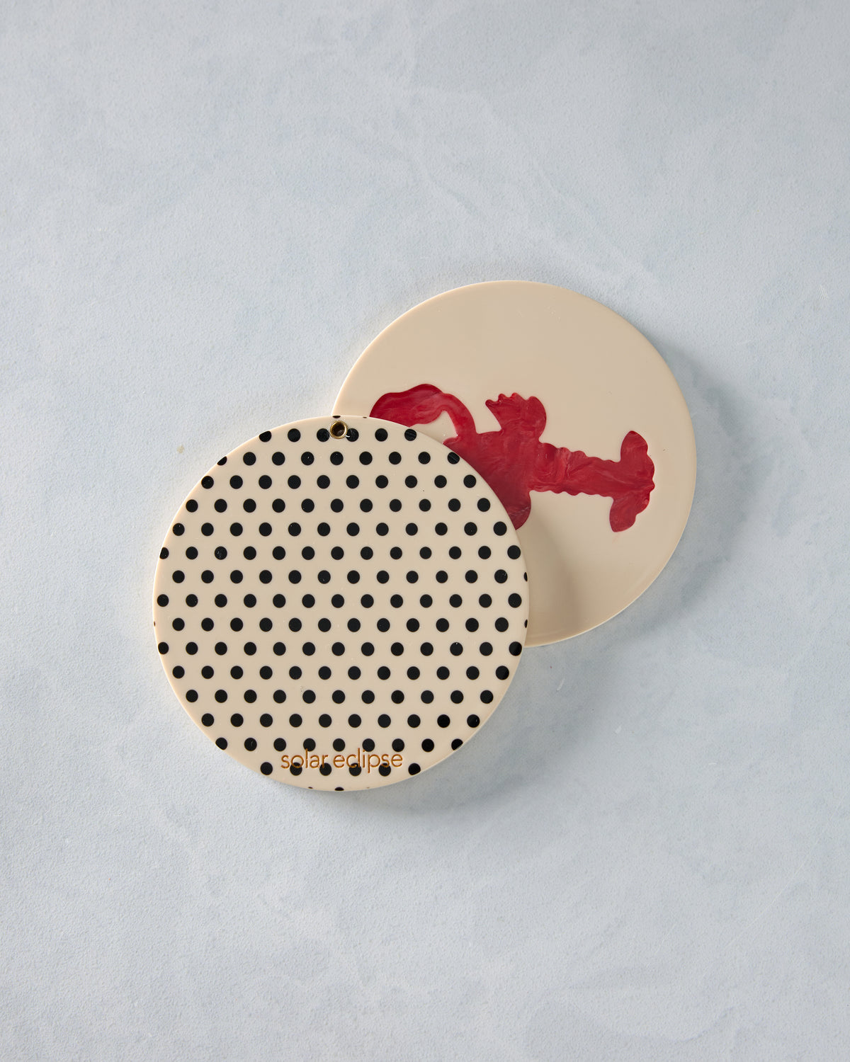 Open round compact mirror with a black dot pattern and a lobster design on the inside cover.