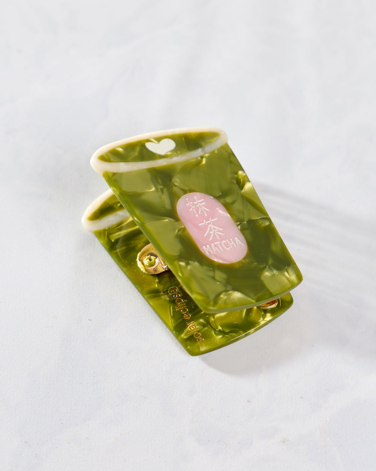 Green hand-painted mini matcha claw hair clip with translucent swirled detailing and a pink MATCHA label
