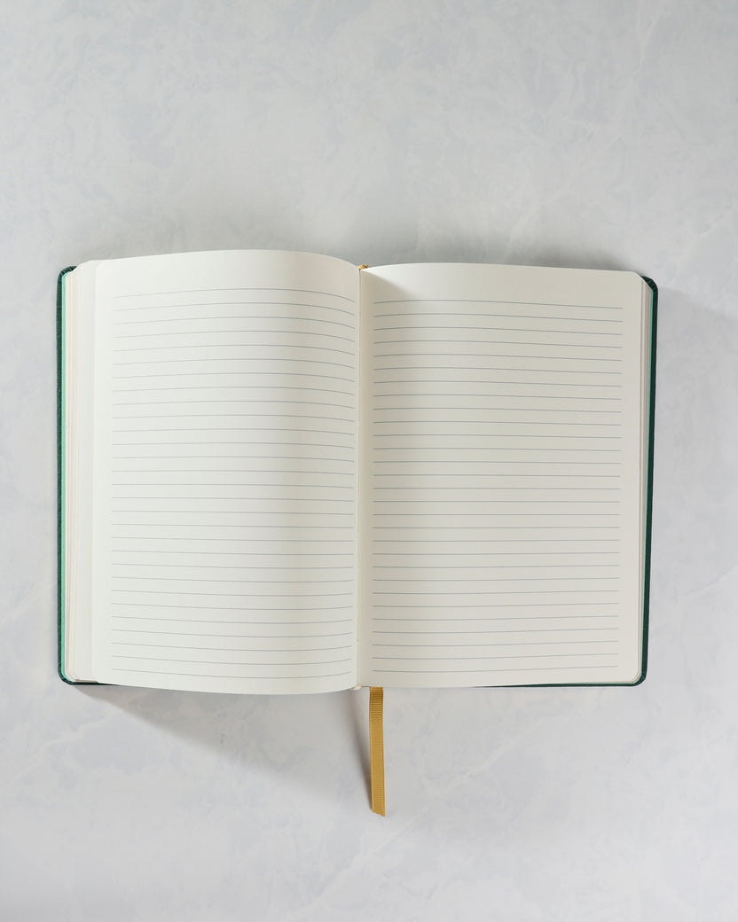Cozy Reads journal opened to two blank ruled pages, with a gold ribbon bookmark visible at the bottom.