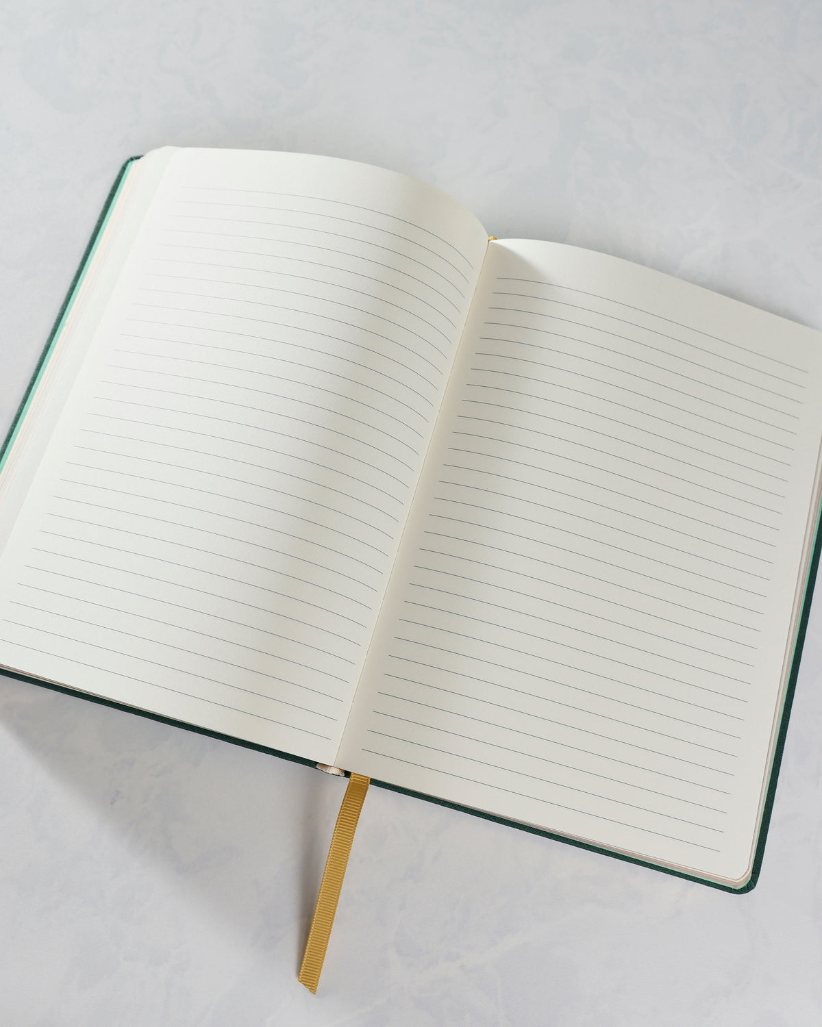 Close angled view of the Cozy Reads journal opened to blank ruled pages, showing the center binding and gold ribbon bookmark.