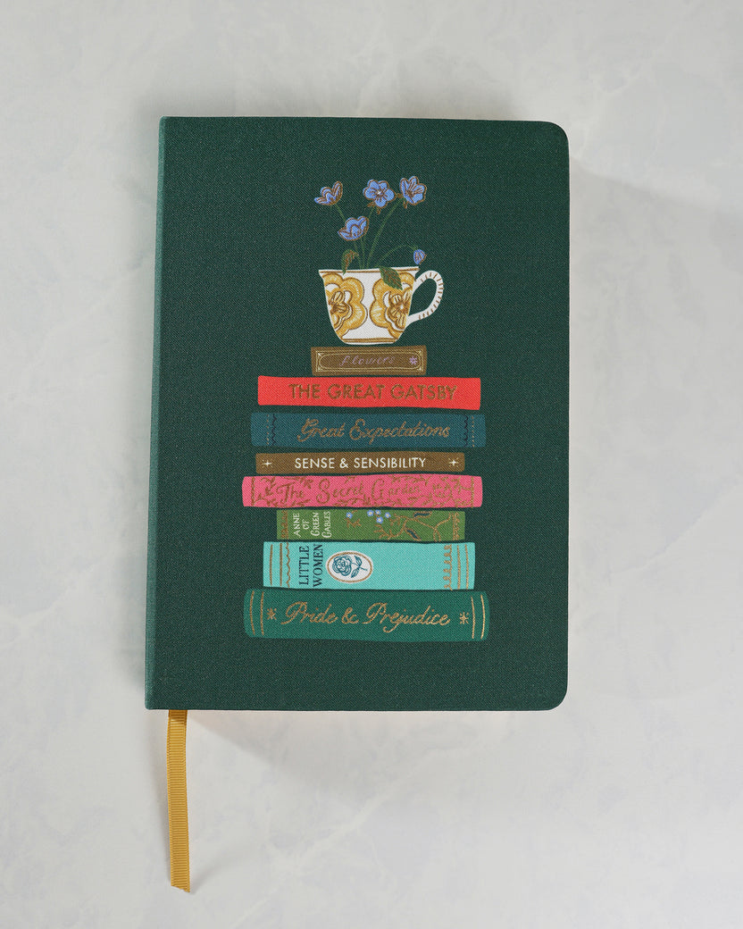 Front cover of a forest-green hardcover journal illustrated with a floral teacup above stacked classic novels.