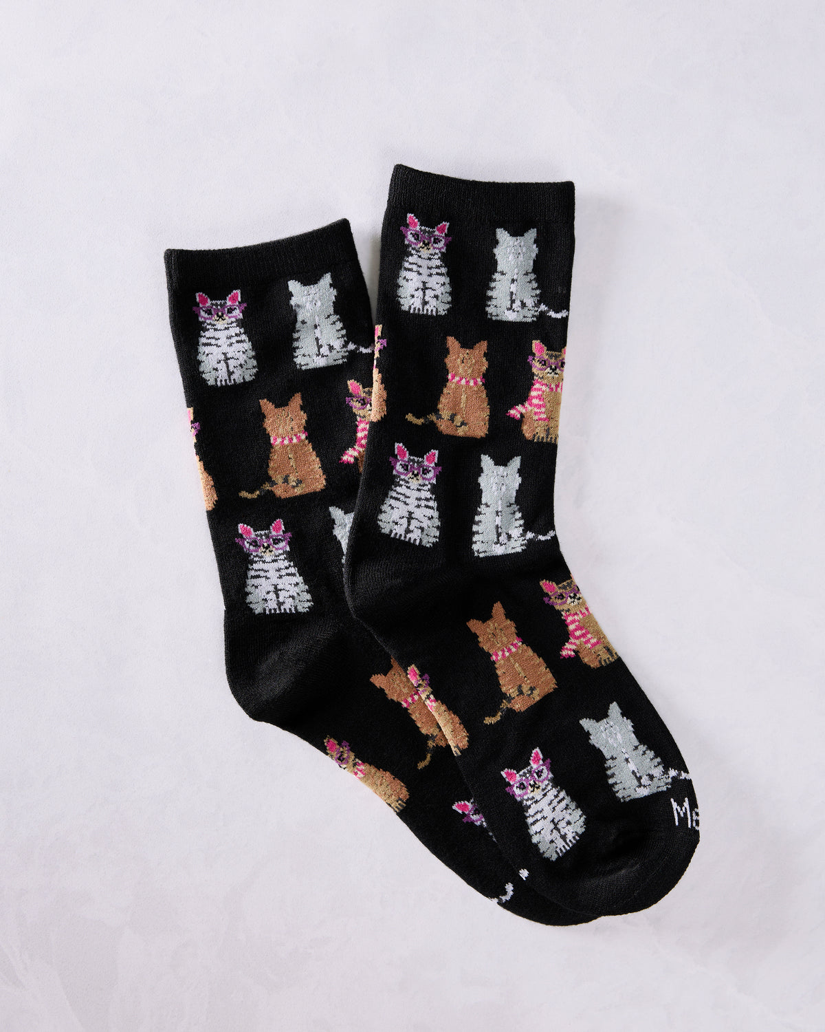 Pair of black crew socks covered with repeated gray and brown cat illustrations, including cats wearing glasses and striped scarves.