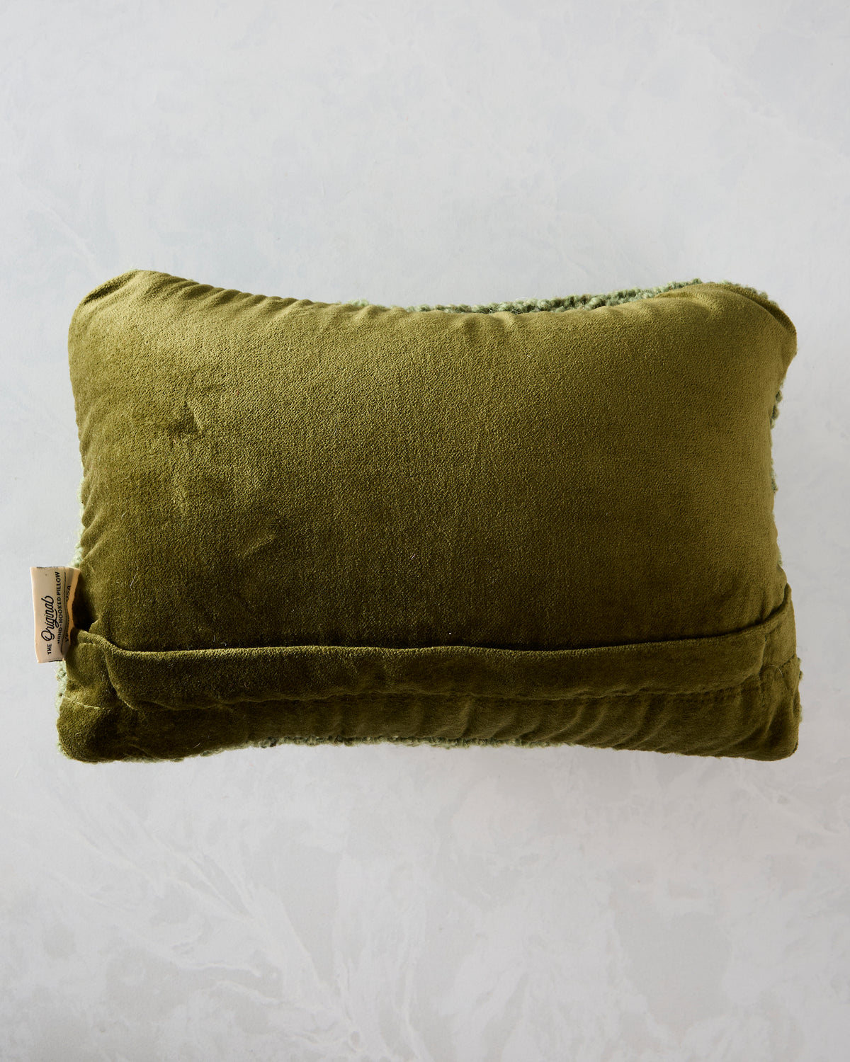 Back of the sunflower pillow, showing a plain green velvet backing, lower seam, and side fabric label.