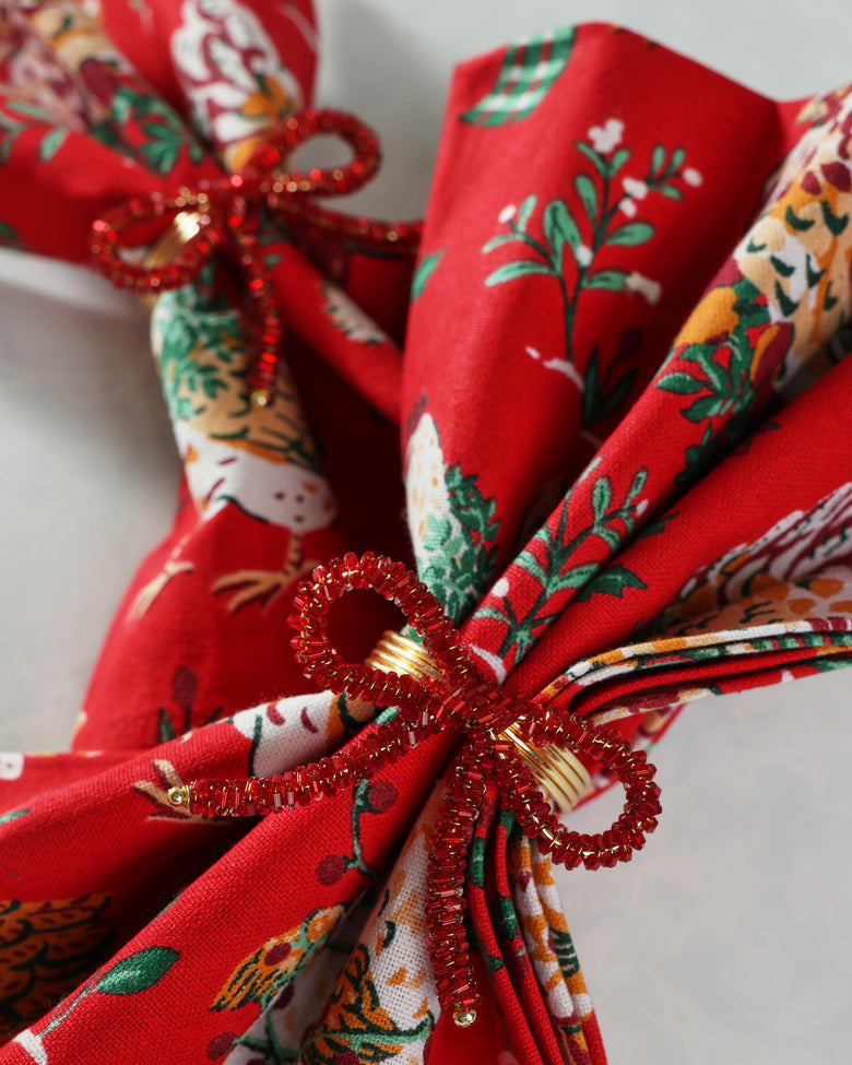 Close-up of a red beaded bow napkin ring around a folded patterned napkin