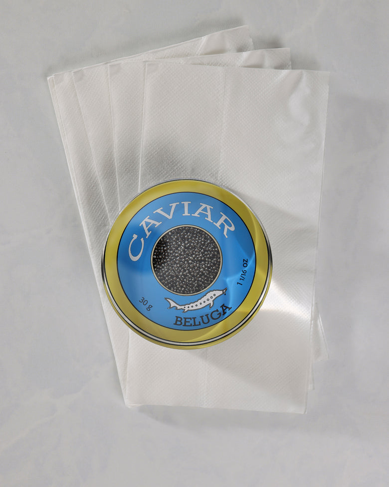 Top view of a round blue-and-gold caviar-themed napkin weight placed on several white napkins.