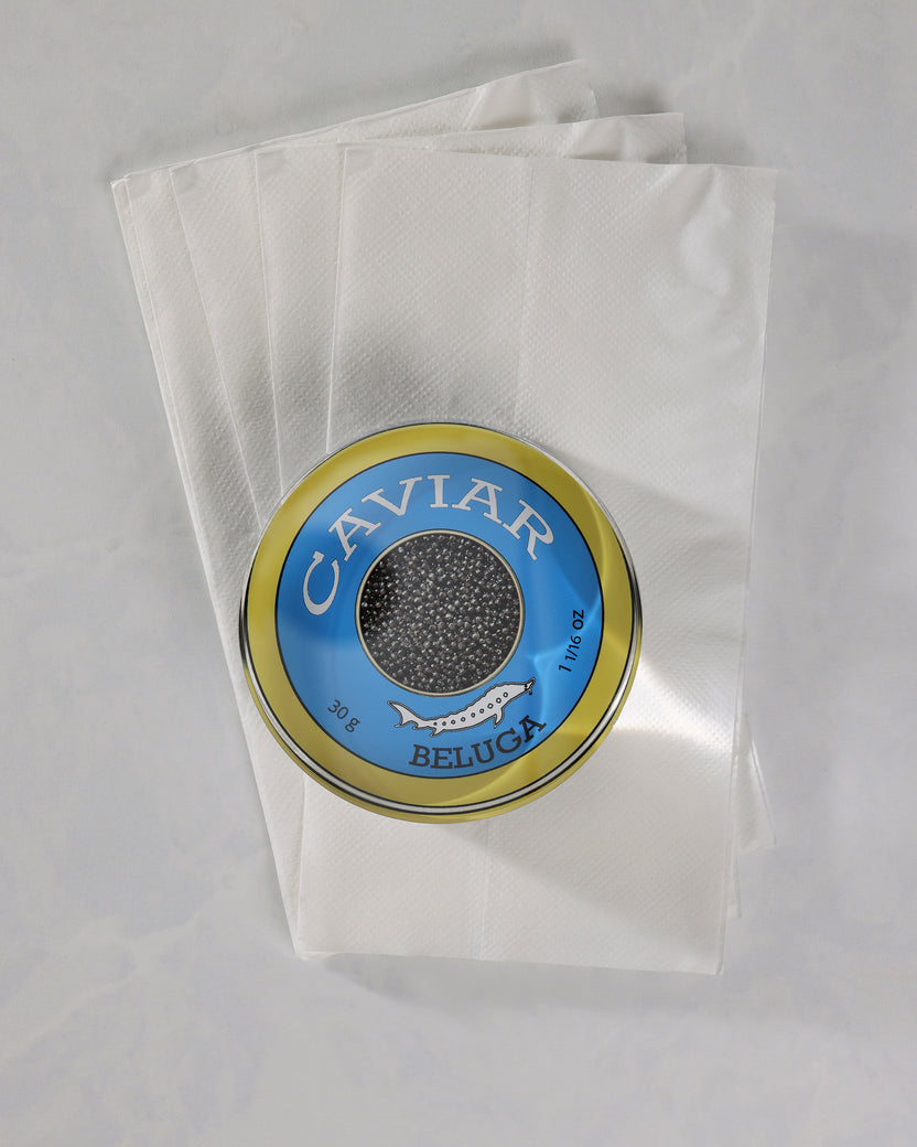 Top view of a round blue-and-gold caviar-themed napkin weight placed on several white napkins.