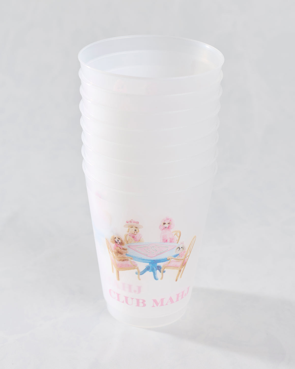 White frosted cup featuring an illustration of dogs gathered around a mahjong table and pink lettering.
