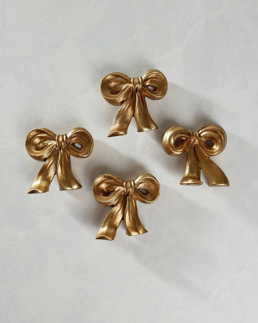 Four gold bow placecard holders arranged separately on a light background.