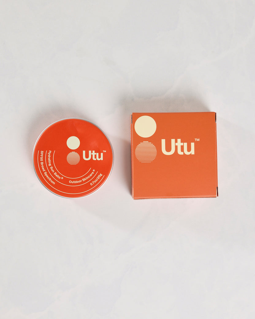 Orange Utu SPF50 Hydrating Sun Balm tin beside its matching box.