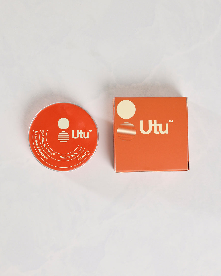 Orange Utu SPF50 Hydrating Sun Balm tin beside its matching box.