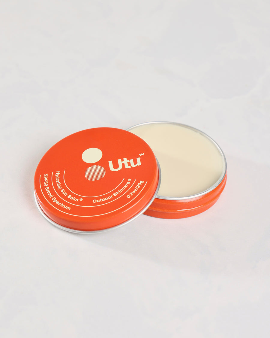 Open orange Utu sun balm tin showing the balm, with its lid in front.