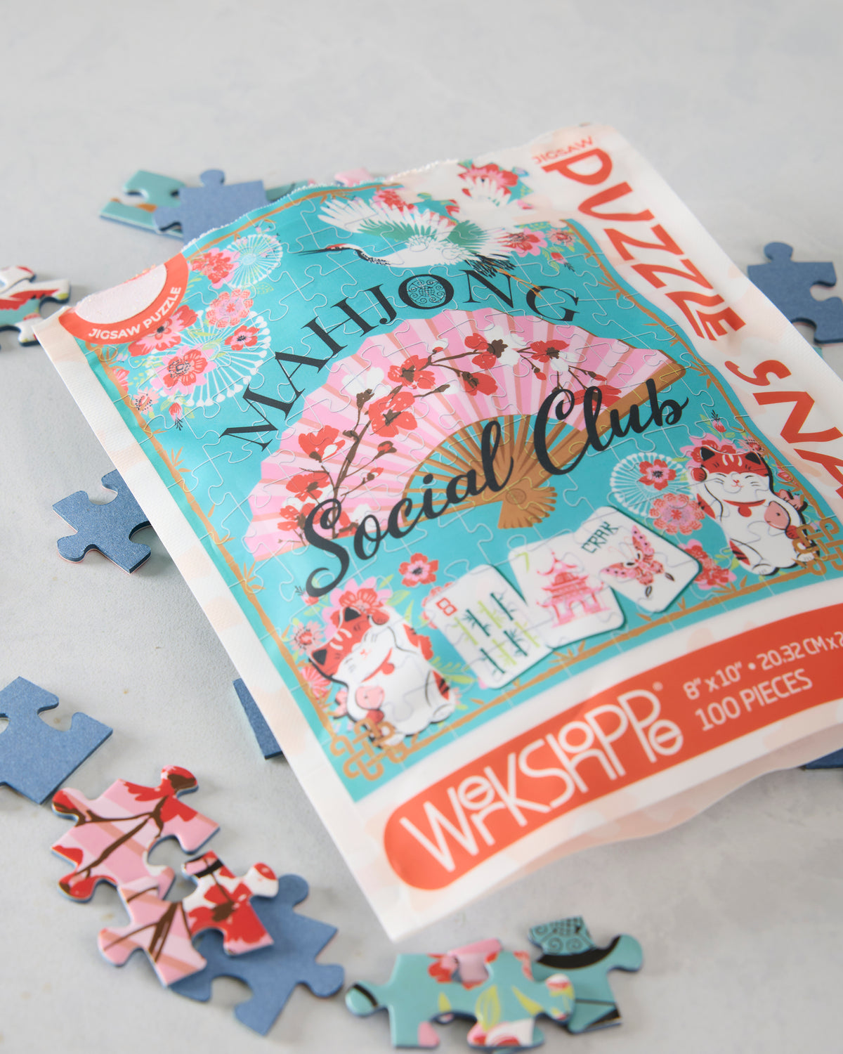 Close angled view of the Mahjong Social Club puzzle pouch with loose pieces around it.
