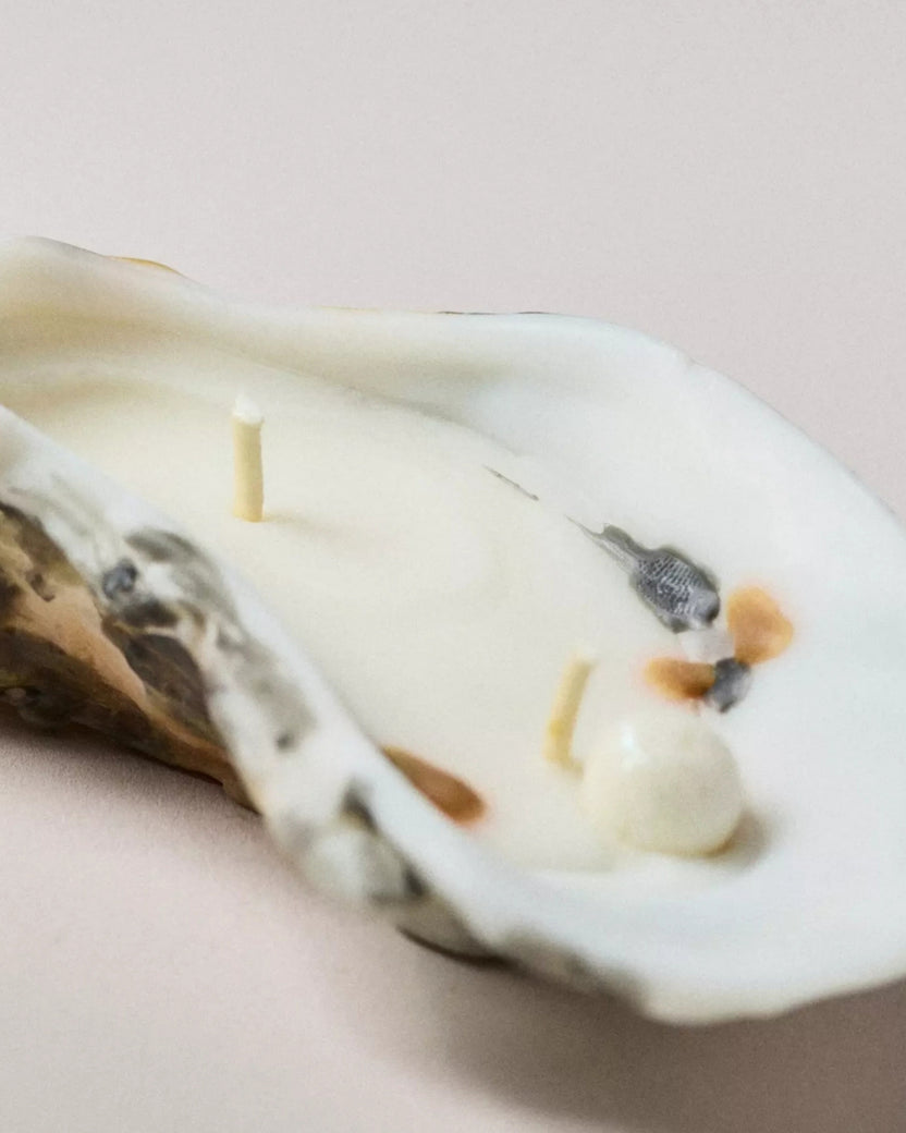 Close-up of the interior of an oyster-shaped candle showing a wick, pearl-like detail, and painted shell details.