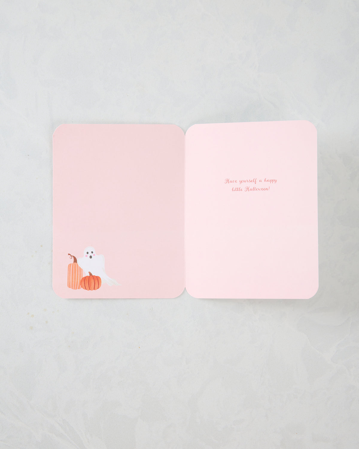 Open pink Halloween greeting card with a white ghost and orange pumpkins on the lower left; inside message reads, “Have yourself a happy little Halloween!”