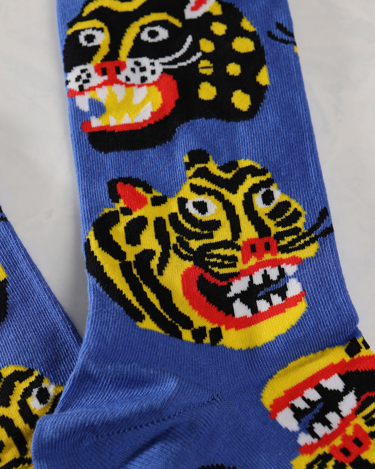 Close-up of blue socks with colorful wild-cat faces and spotted animal patterns.