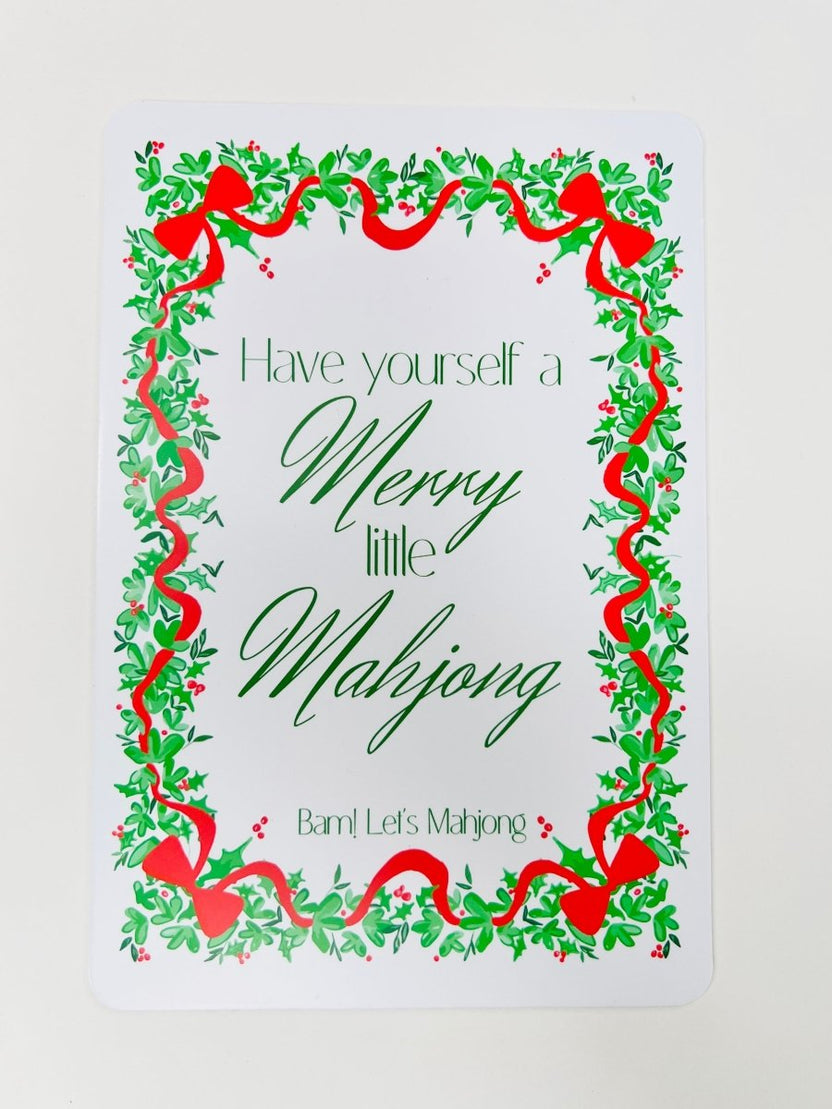 White Christmas Mahjong shuffler card with a leafy green and red ribbon border and the phrase “Have yourself a Merry little Mahjong.”