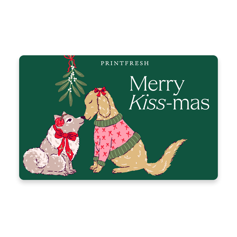 Green illustrated gift card showing two dogs beneath mistletoe with the message “Merry Kiss-mas.”