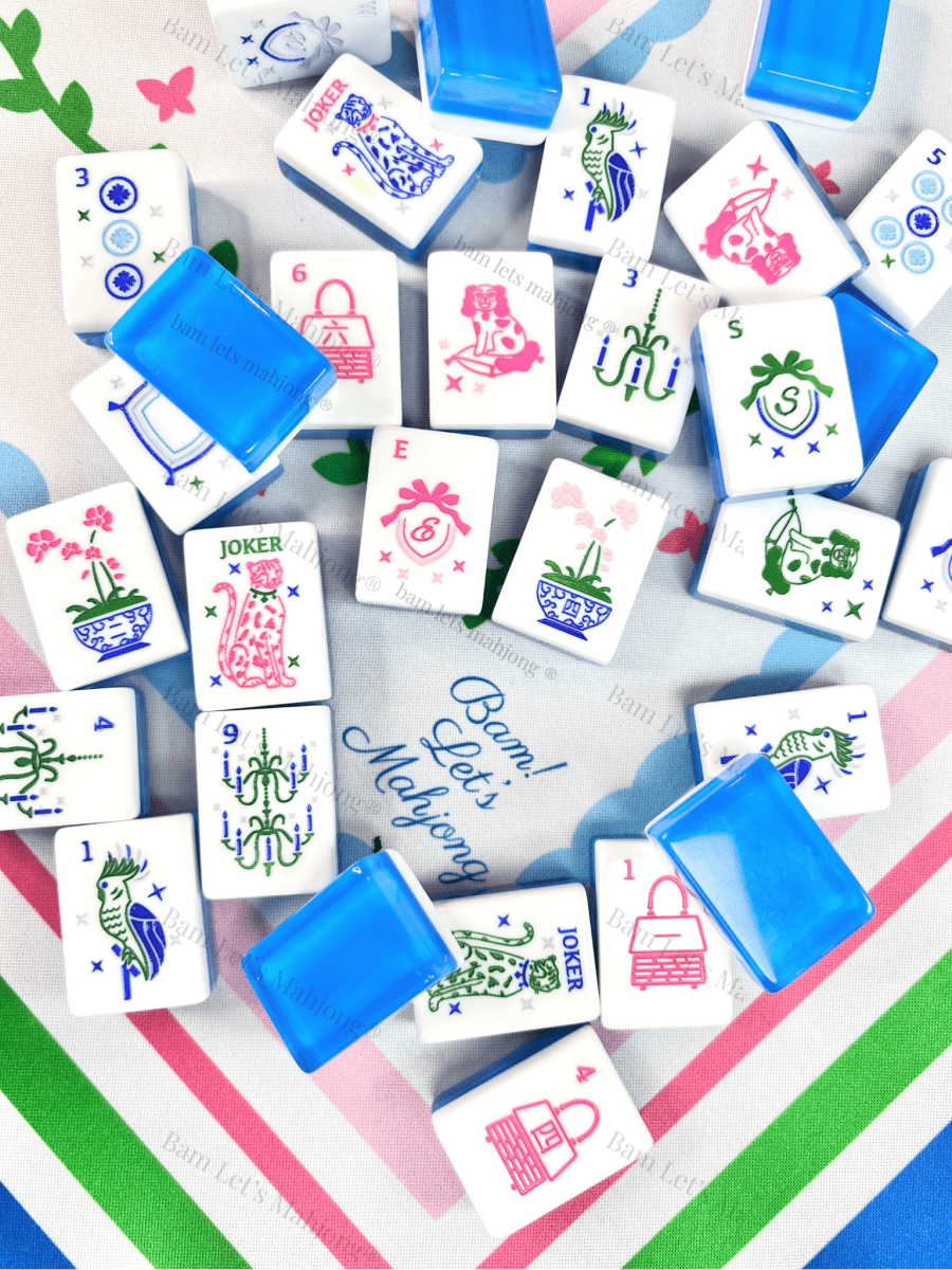 Blue, pink, and green patterned mahjong mat styled with colorful nautical and floral mahjong tiles and blue tile shufflers.