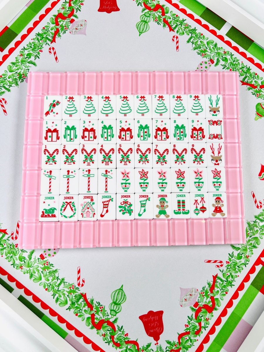 Overhead view of the complete holiday mahjong tile set arranged in rows inside a pink tile rack, with numbered suits and joker tiles.