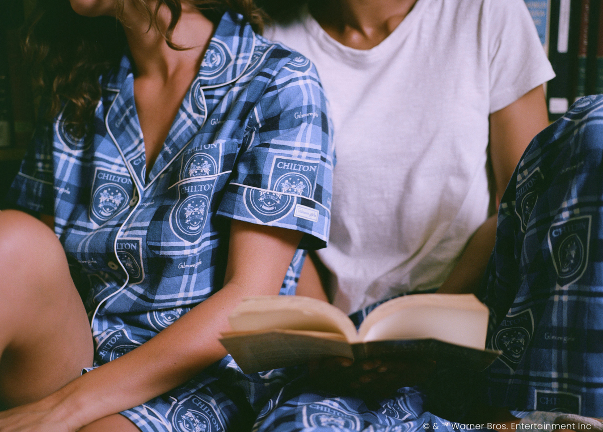People in blue plaid pajama sets sit together while one holds an open book.